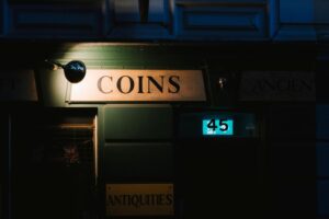 A vintage coin shop illuminated at night, showcasing signs and a streetlight.